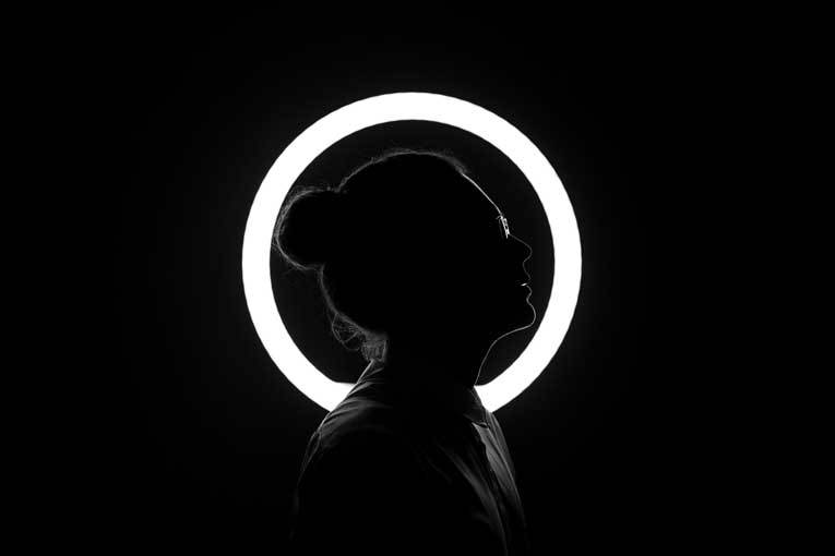 Black and white portrait of person in front of illuminated halo image