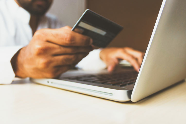 Man typing bank card number on laptop image