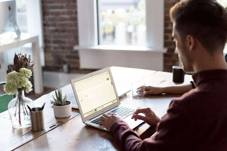 Man typing on his laptop on his desk image